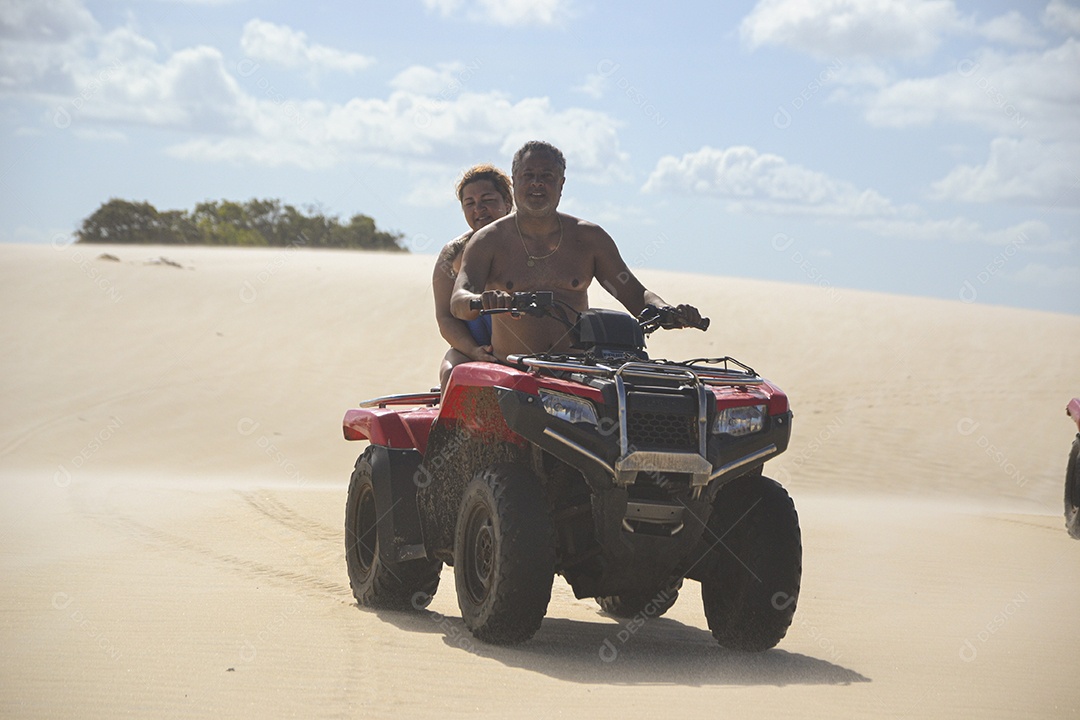 Casal feliz andando de quadriciclo na praia