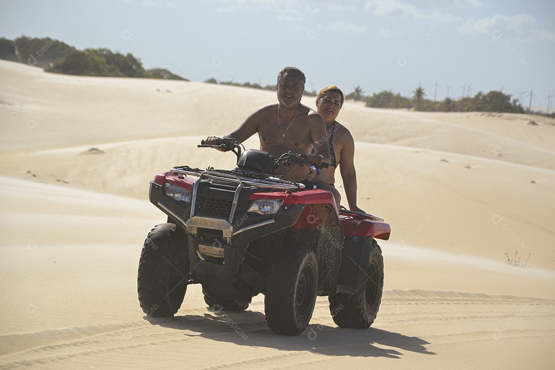 Casal feliz andando de quadriciclo na praia