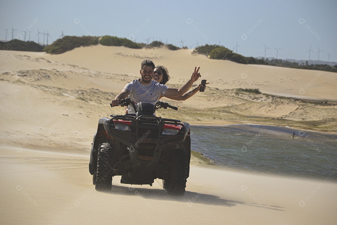 Casal feliz andando de quadriciclo na praia