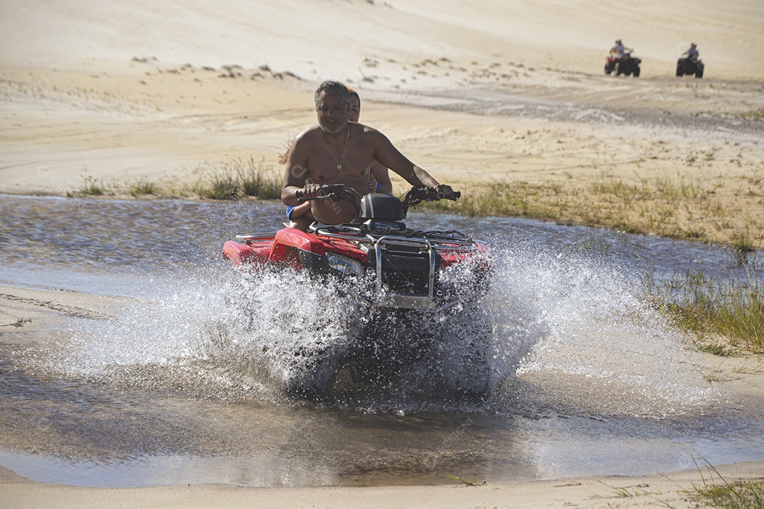 Casal feliz andando de quadriciclo na praia