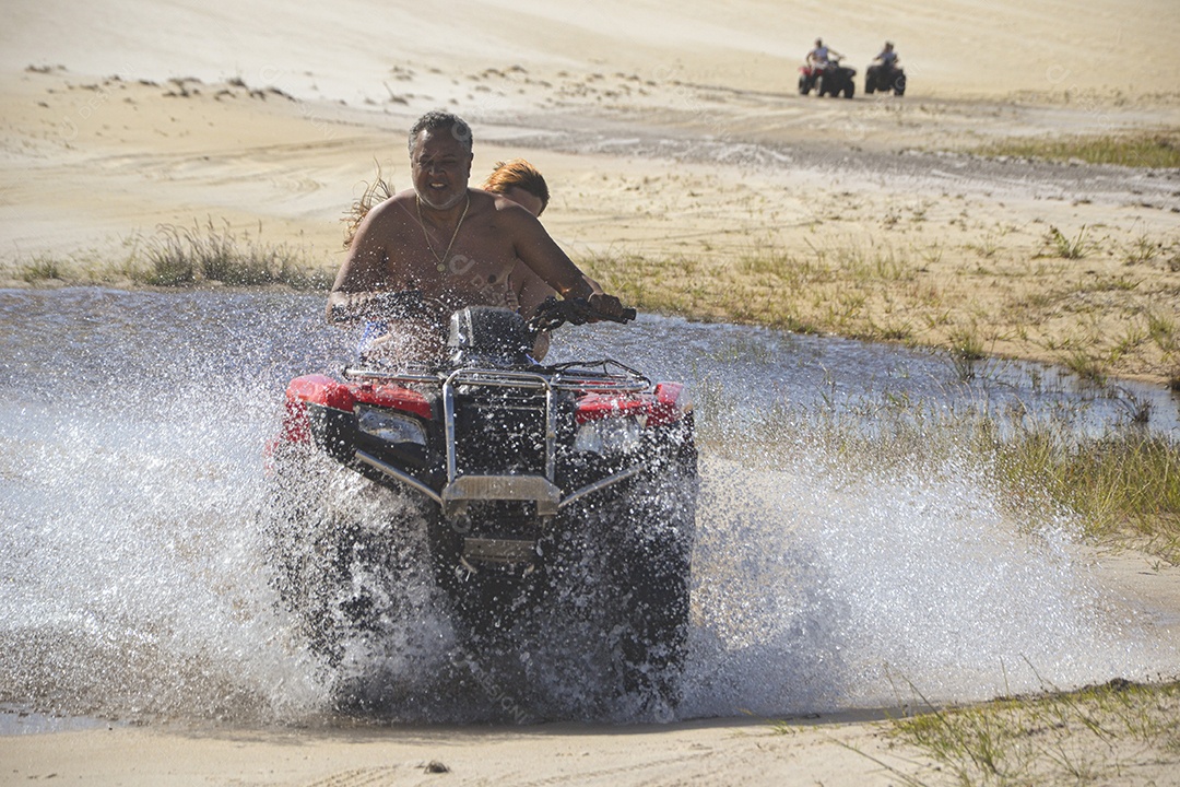 Casal feliz andando de quadriciclo na praia
