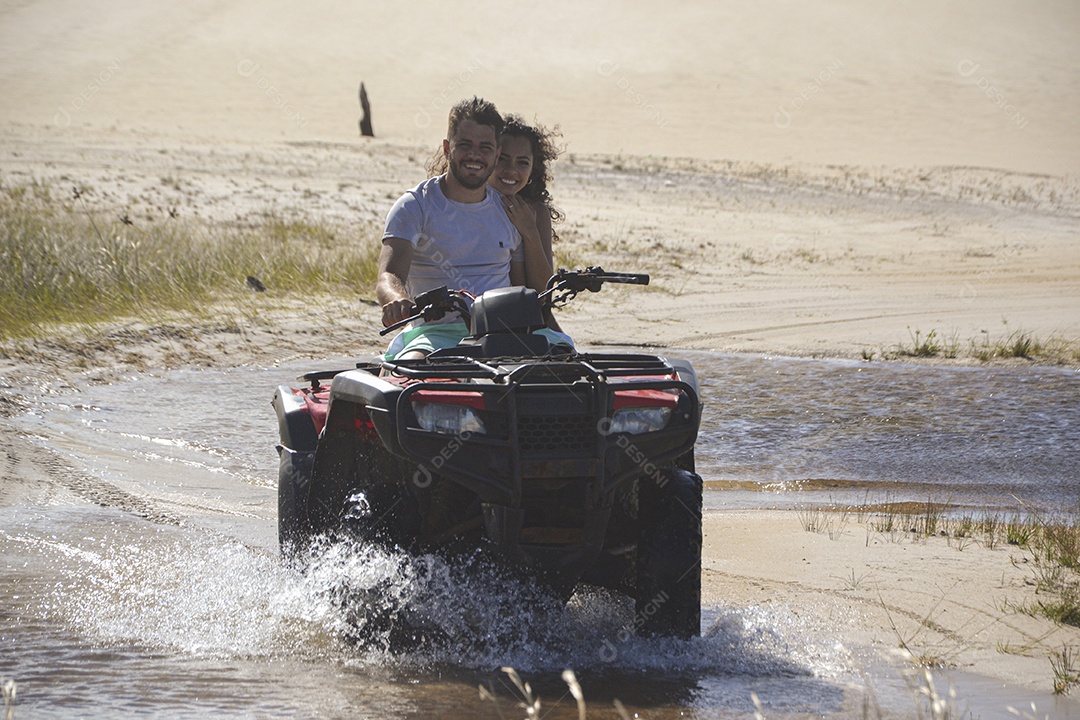 Casal feliz andando de quadriciclo na praia