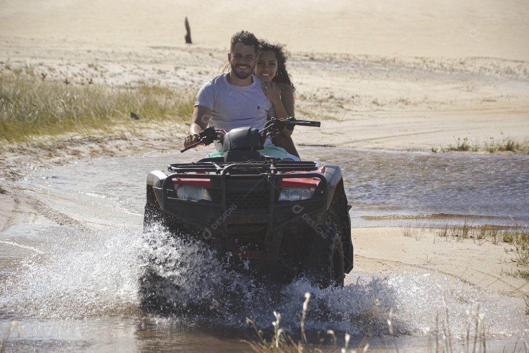Casal feliz andando de quadriciclo na praia
