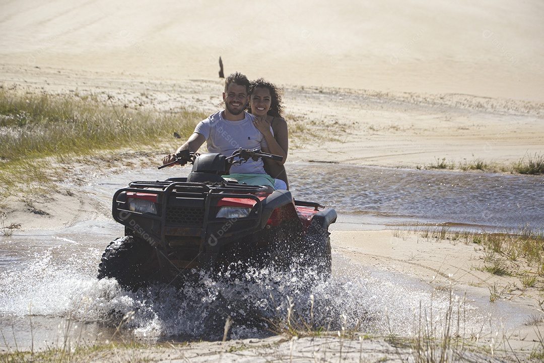 Casal feliz andando de quadriciclo na praia