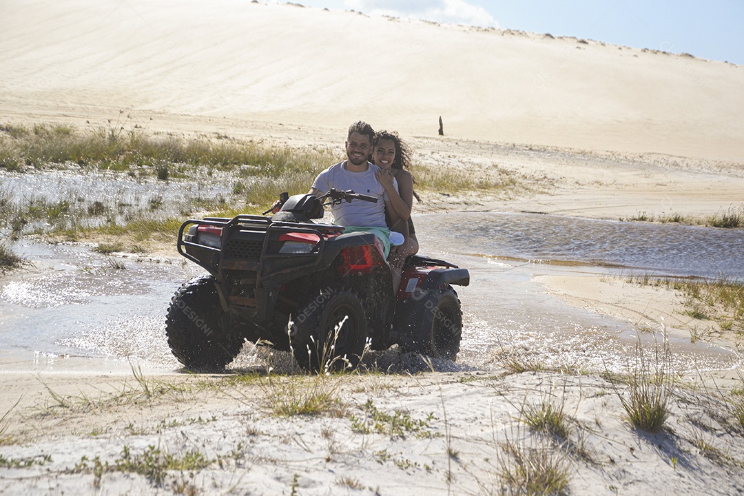 Casal feliz andando de quadriciclo na praia