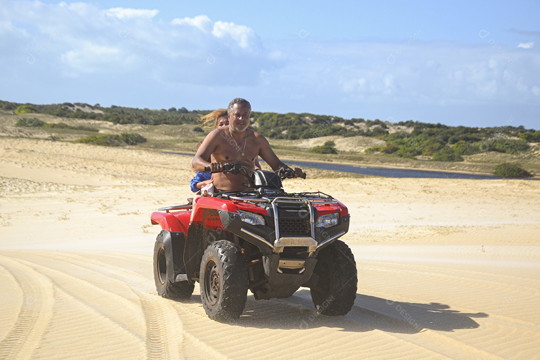 Casal feliz andando de quadriciclo na praia