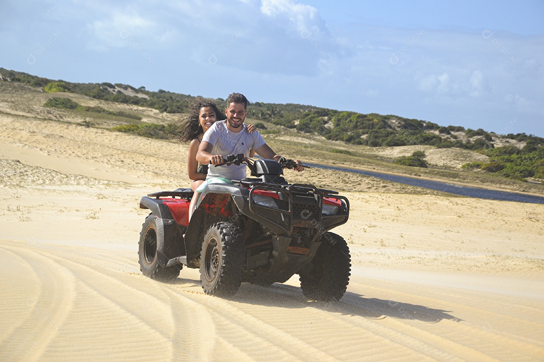 Casal feliz andando de quadriciclo na praia