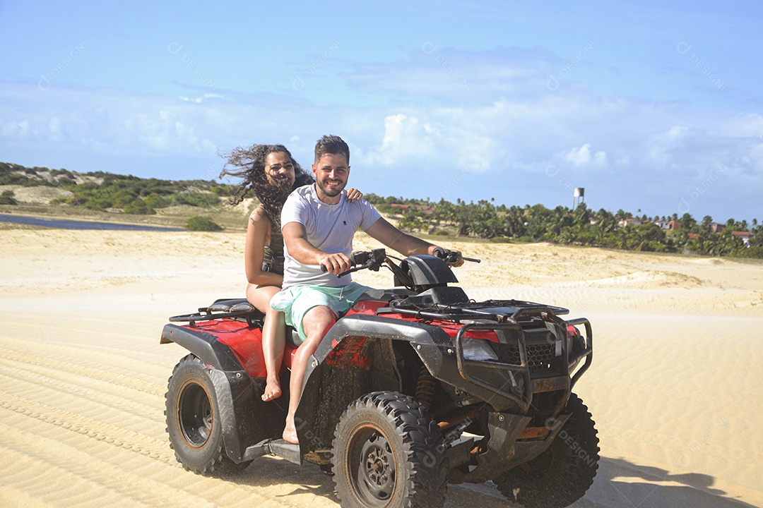 Casal feliz andando de quadriciclo na praia