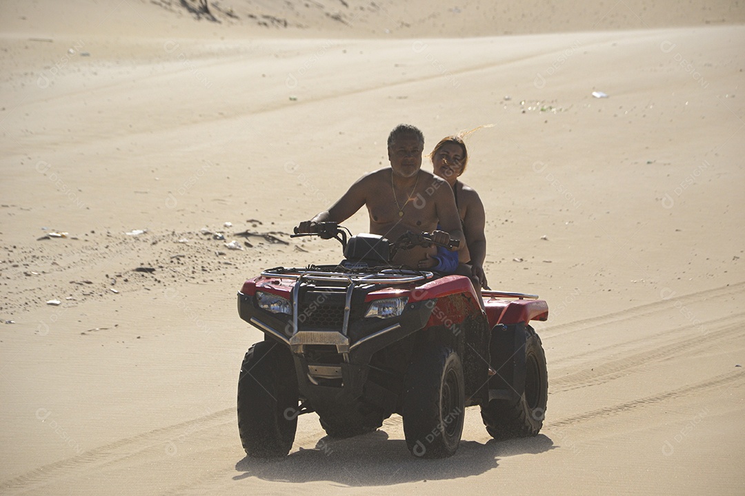 Casal feliz andando de quadriciclo na praia