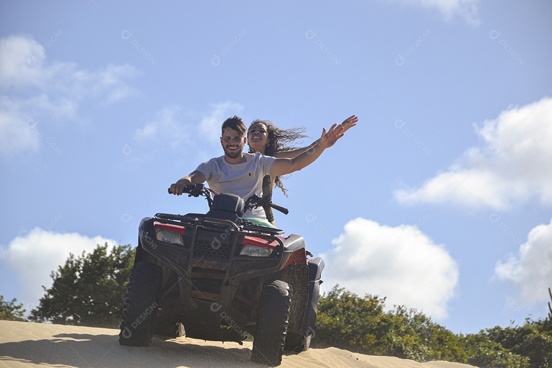 Casal feliz andando de quadriciclo na praia