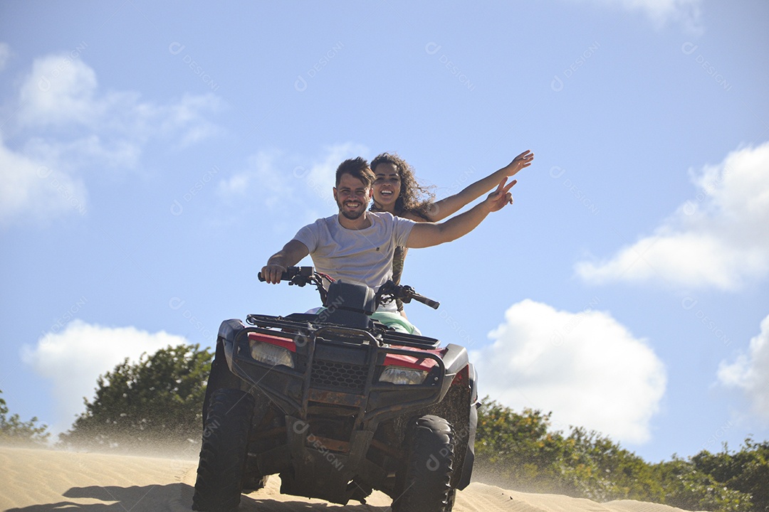 Casal feliz andando de quadriciclo na praia