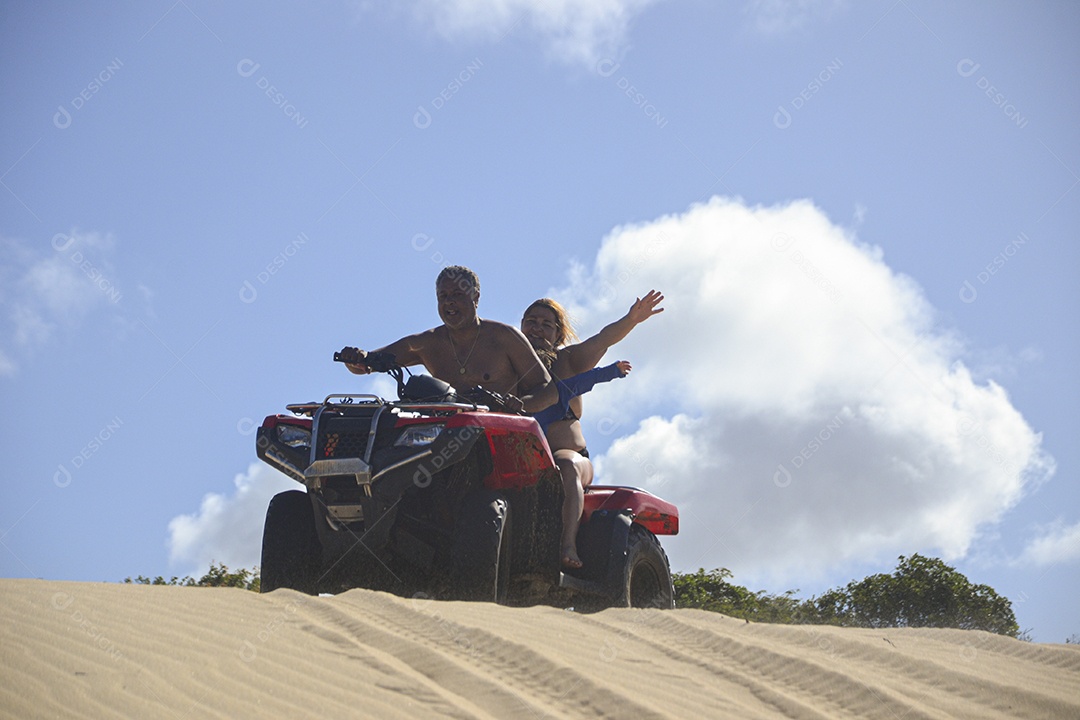 Casal feliz andando de quadriciclo na praia