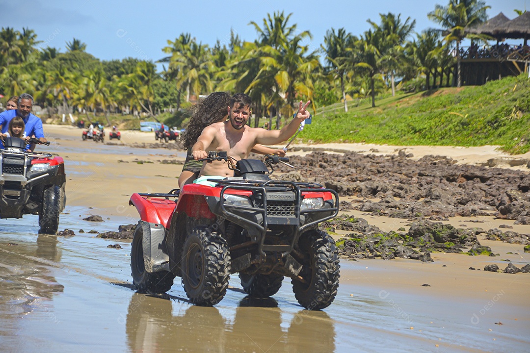 Casal feliz andando de quadriciclo na praia