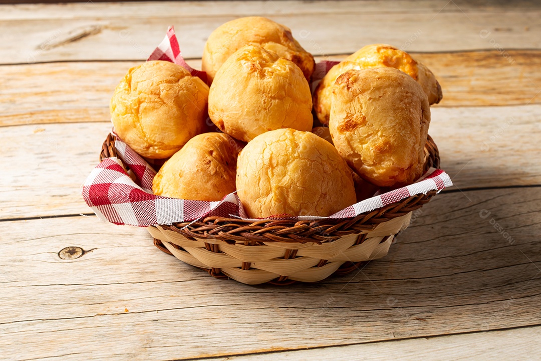 Pães de queijo em cesta sobre mesa de madeira