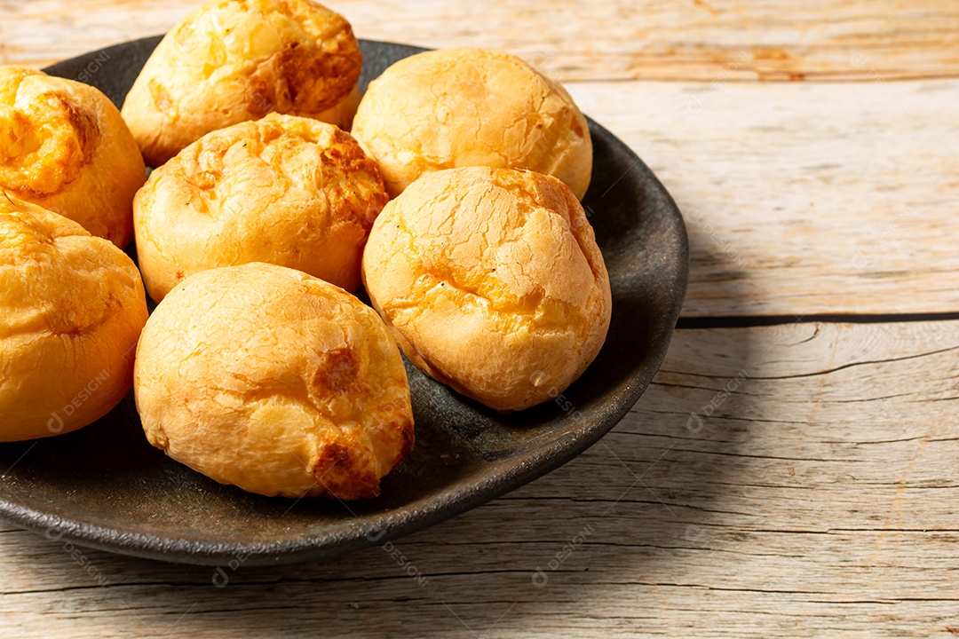 Pães de queijo em cesta sobre mesa de madeira