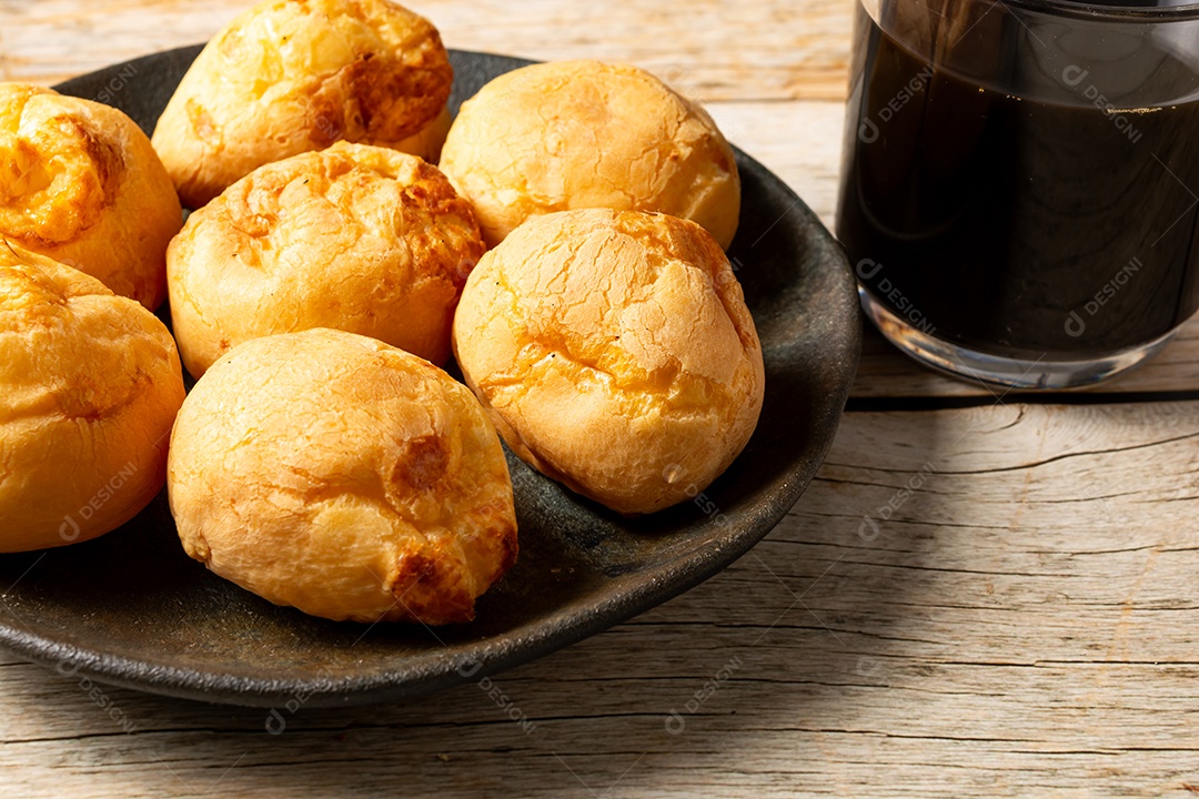 Pães de queijo em cesta sobre mesa de madeira