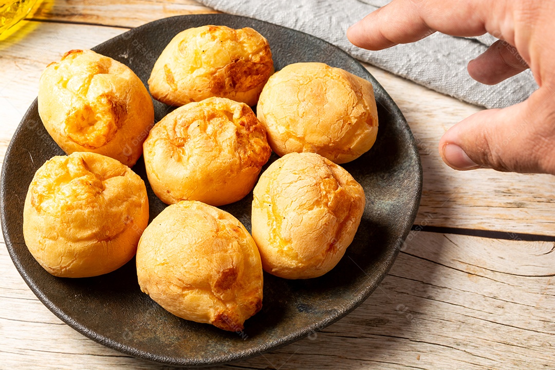 Pães de queijo em cesta sobre mesa de madeira