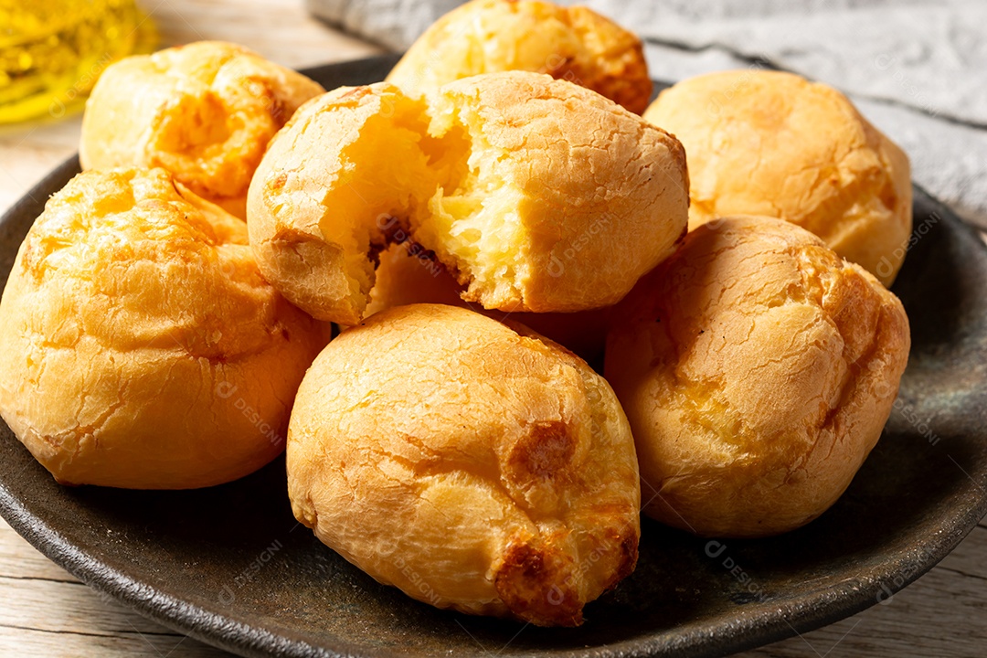 Pães de queijo em cesta sobre mesa de madeira