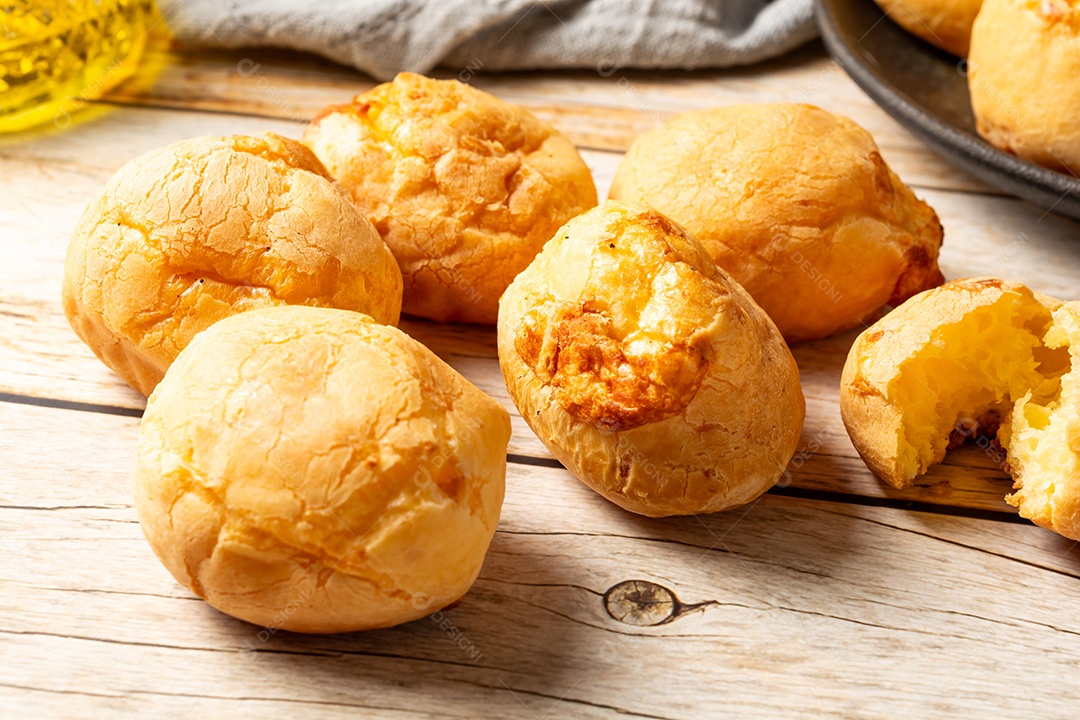Pães de queijo em cesta sobre mesa de madeira