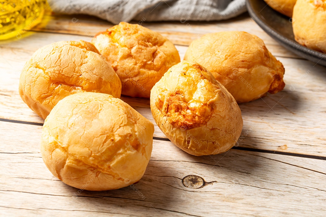 Pães de queijo em cesta sobre mesa de madeira