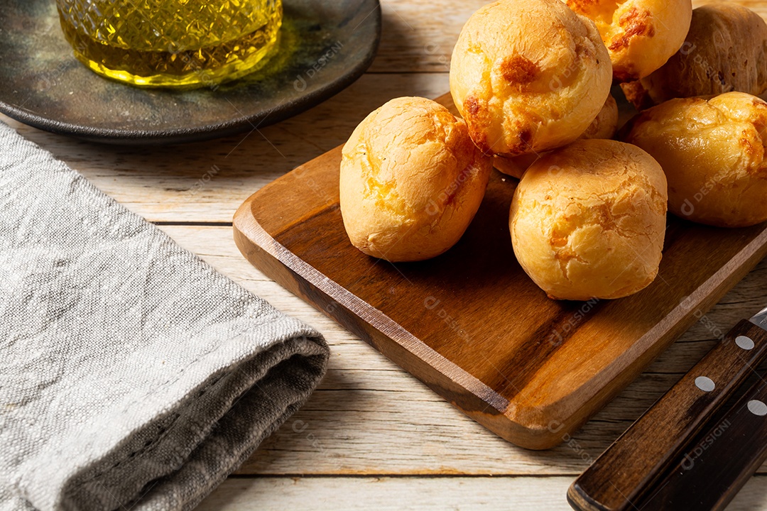 Pães de queijo em cesta sobre mesa de madeira