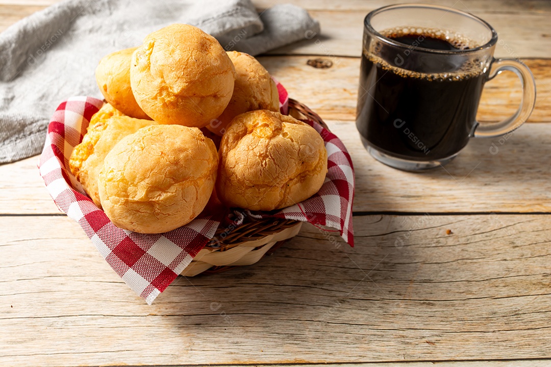 Pão de queijo em mesa de madeira com café preto