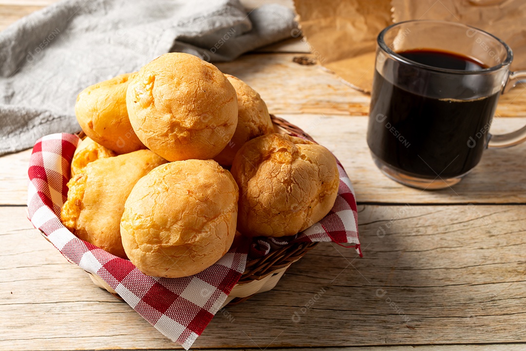 Pão de queijo em mesa de madeira com café preto