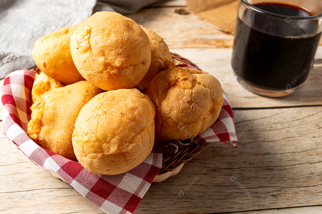 Pão de queijo em mesa de madeira com café preto