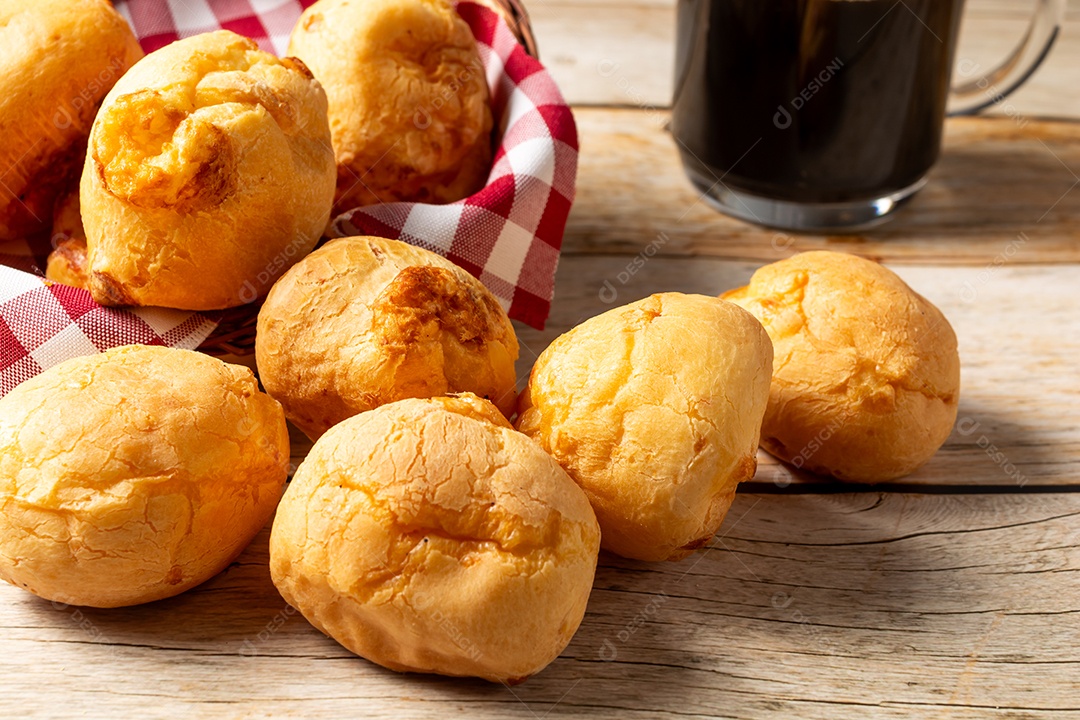 Pão de queijo em mesa de madeira com café preto