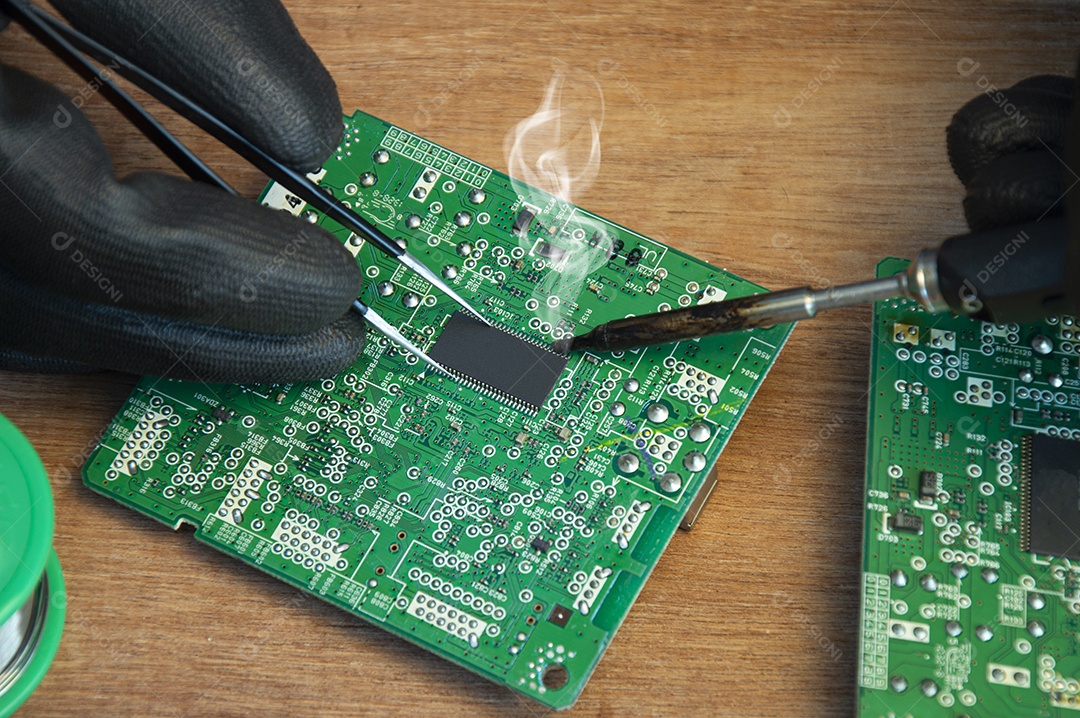 Técnico soldando peças de uma placa mãe