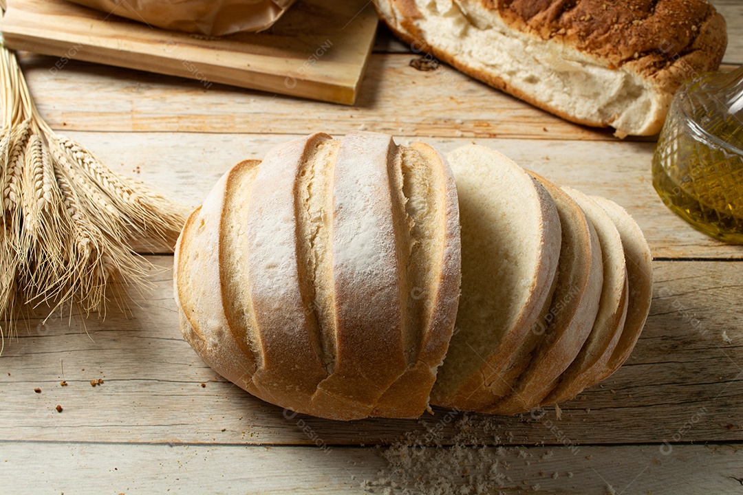 Homem cortando uma fatia de pão redondo em uma mesa de madeira