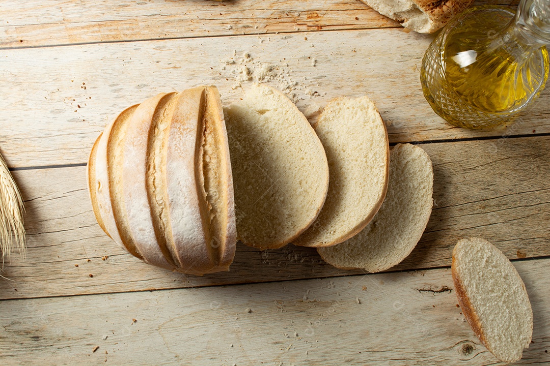 Homem cortando uma fatia de pão redondo em uma mesa de madeira