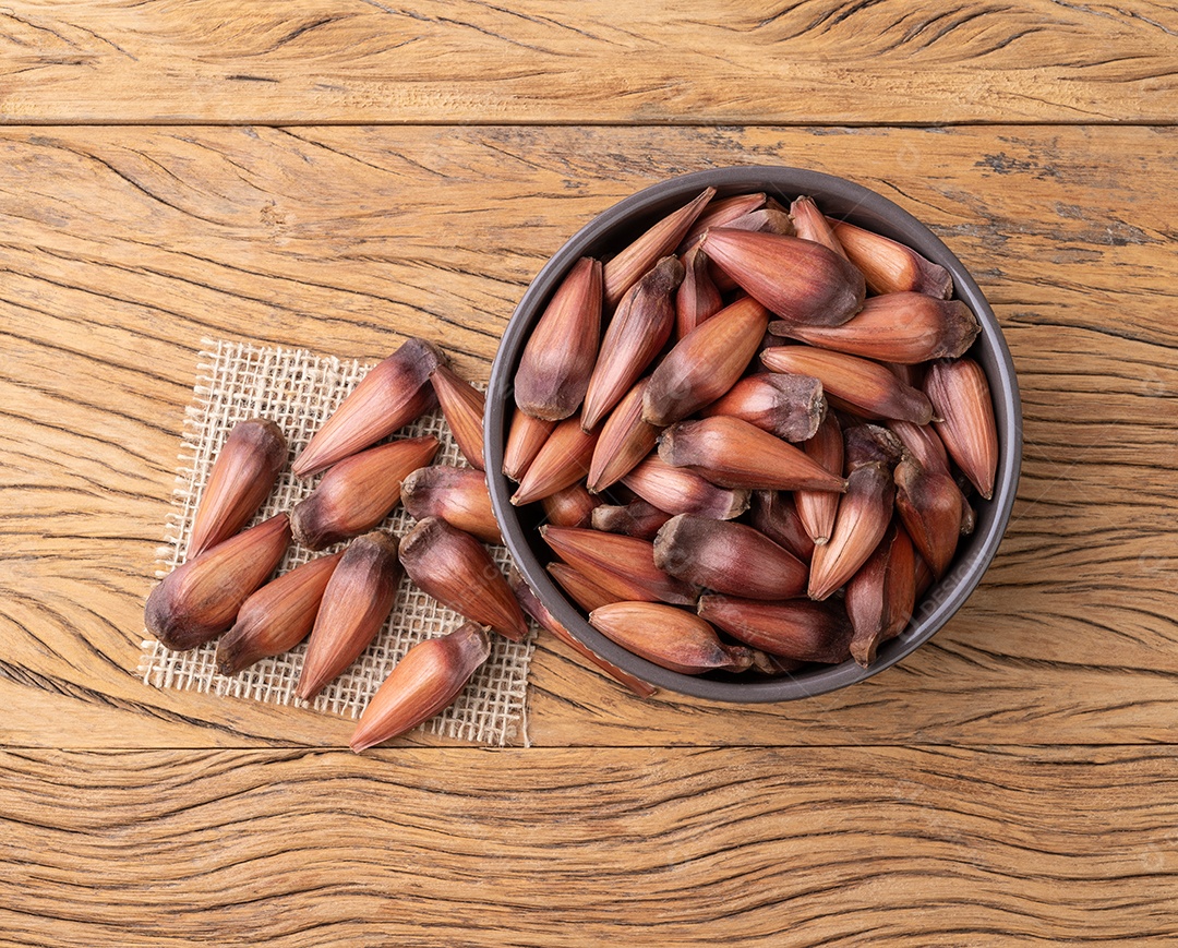 Pinhões ou sementes de pinheiro em uma tigela sobre a mesa de madeira.