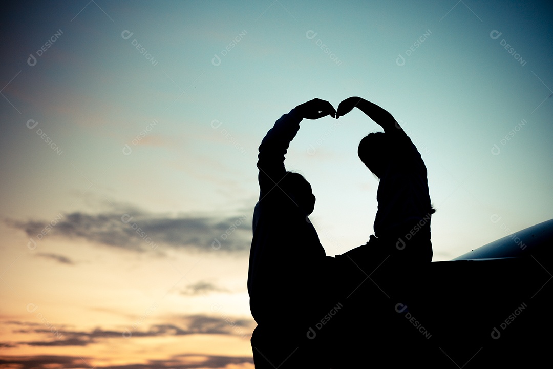Silhueta de uma garota sentada na parte de trás do carro e aproveitando sua mãe e o pôr do sol laranja