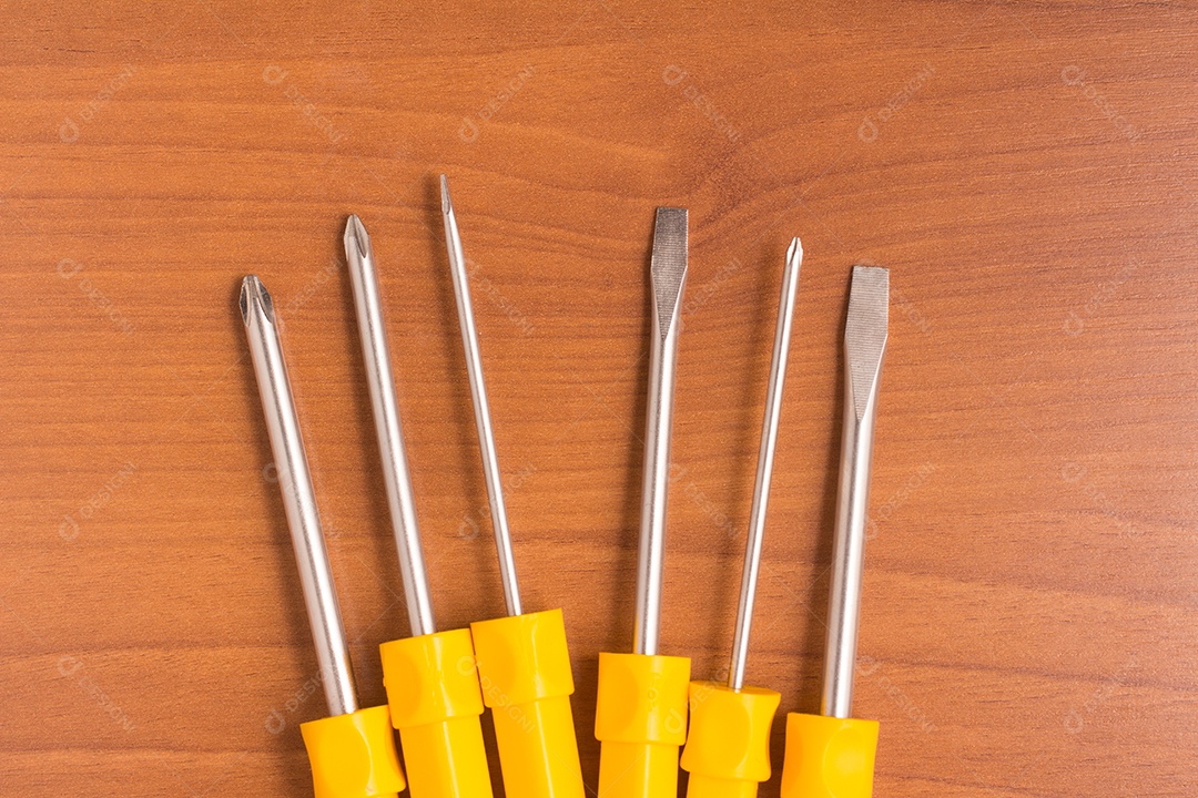 Seis chaves de fenda amarelas sobre uma mesa de madeira