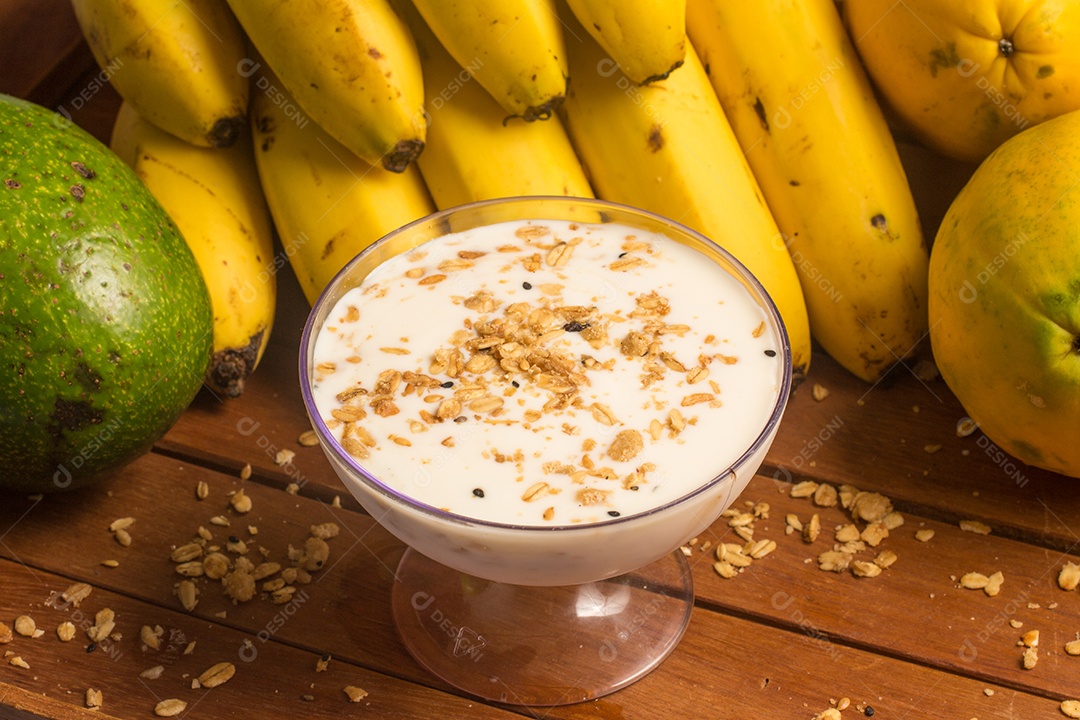 Banana, Mamão, Abacate, Granola e Iogurte sobre uma mesa de madeira