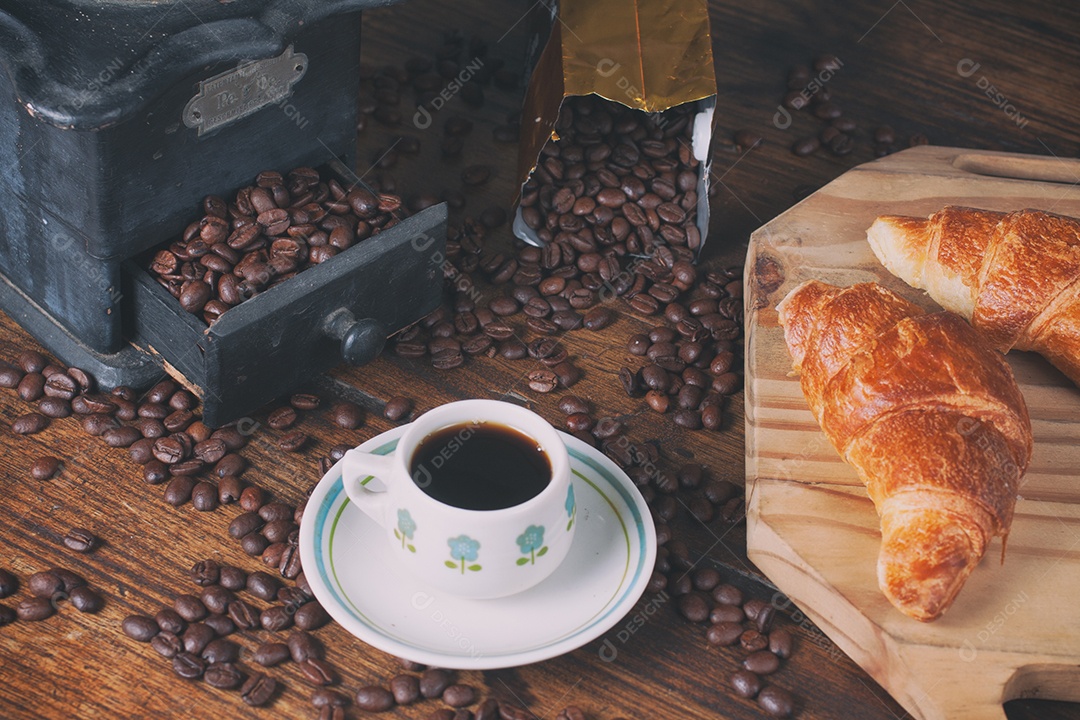 Moedor de café antigo, grãos de café, croissant e xícara