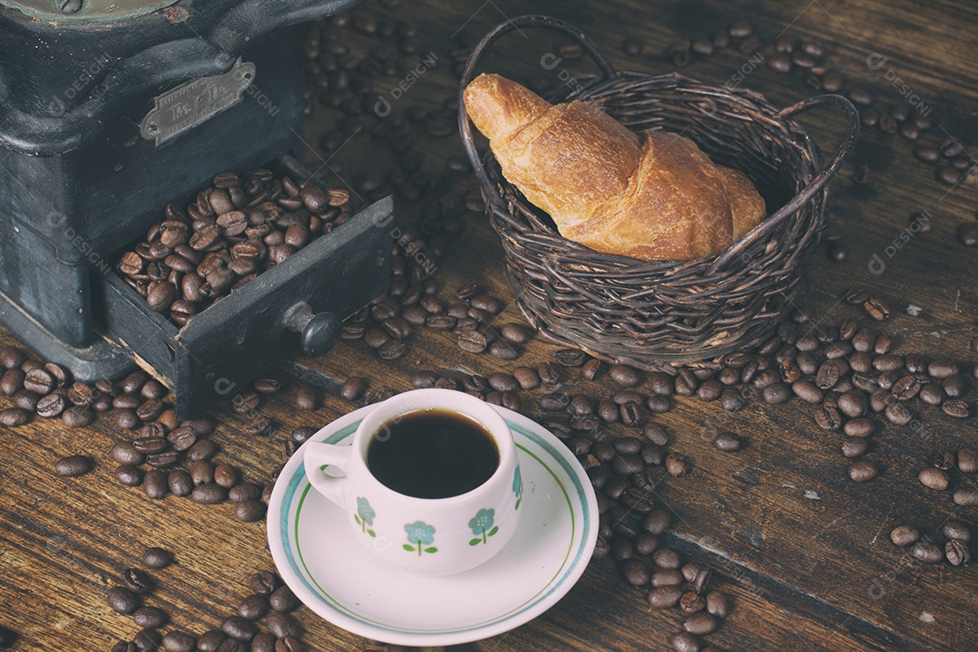 Moedor de café antigo, grãos de café, croissant e xícara