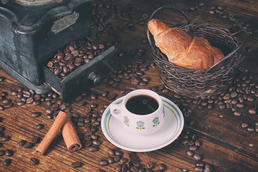 Moedor de café antigo, grãos de café, croissant e xícara