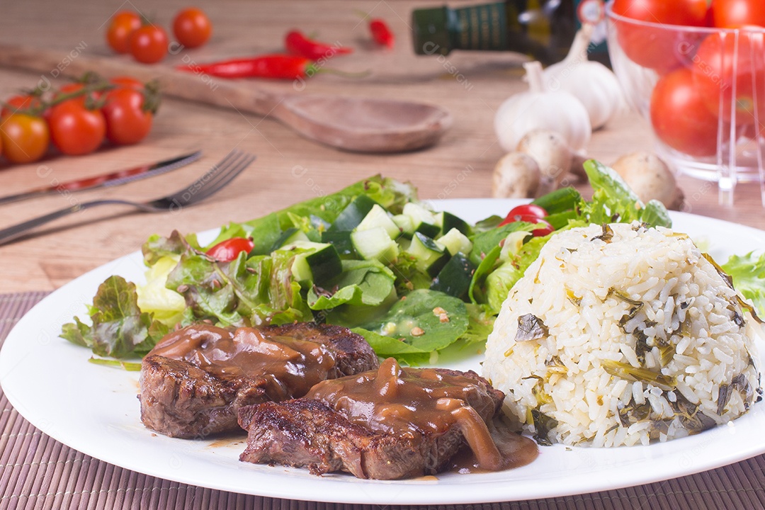 Filé mignon, arroz e salada fresca e saudável sobre uma mesa de madeira