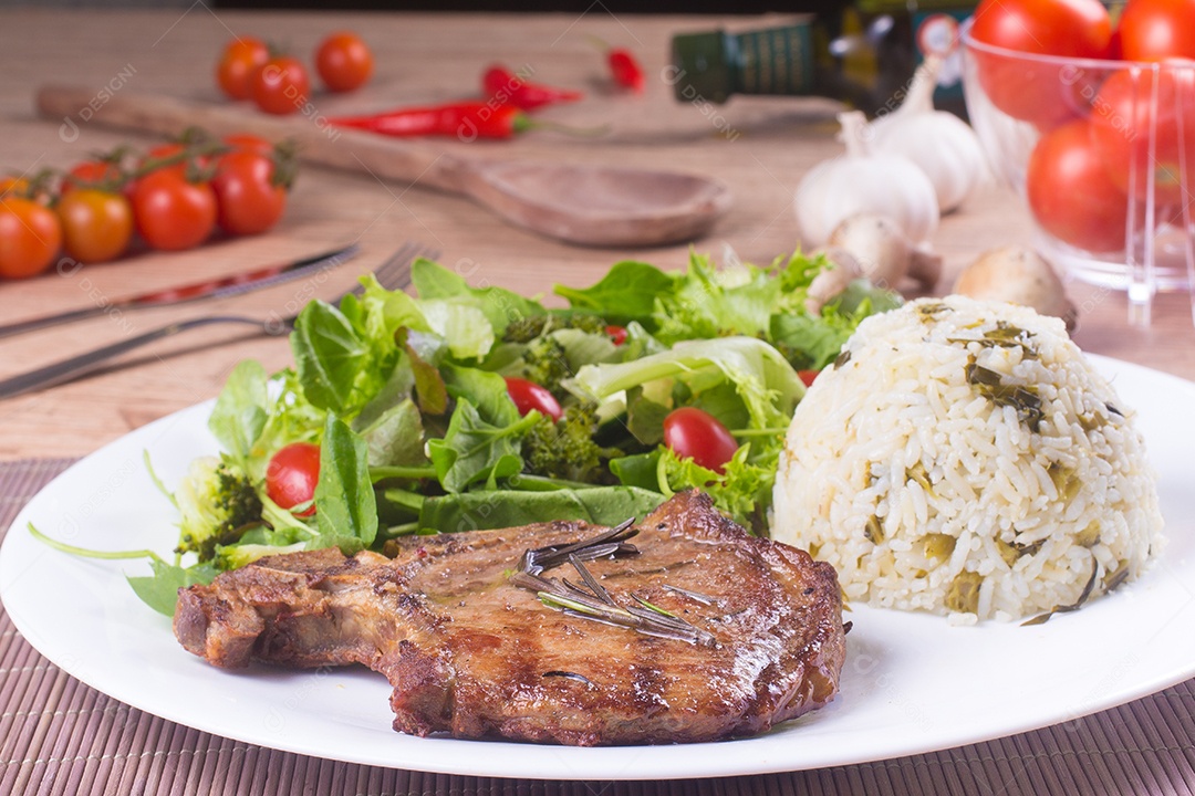Bife de porco, arroz e salada fresca e saudável sobre uma mesa de madeira