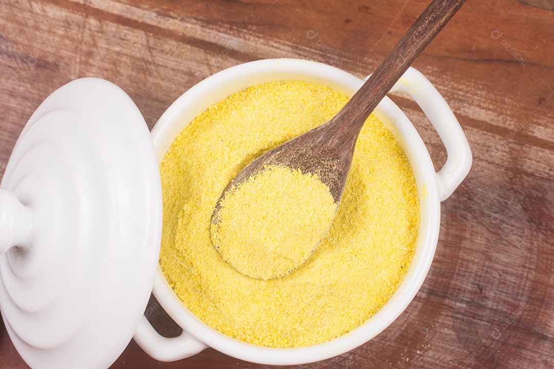 Farinha de mandioca amarela em uma tigela sobre uma mesa de madeira