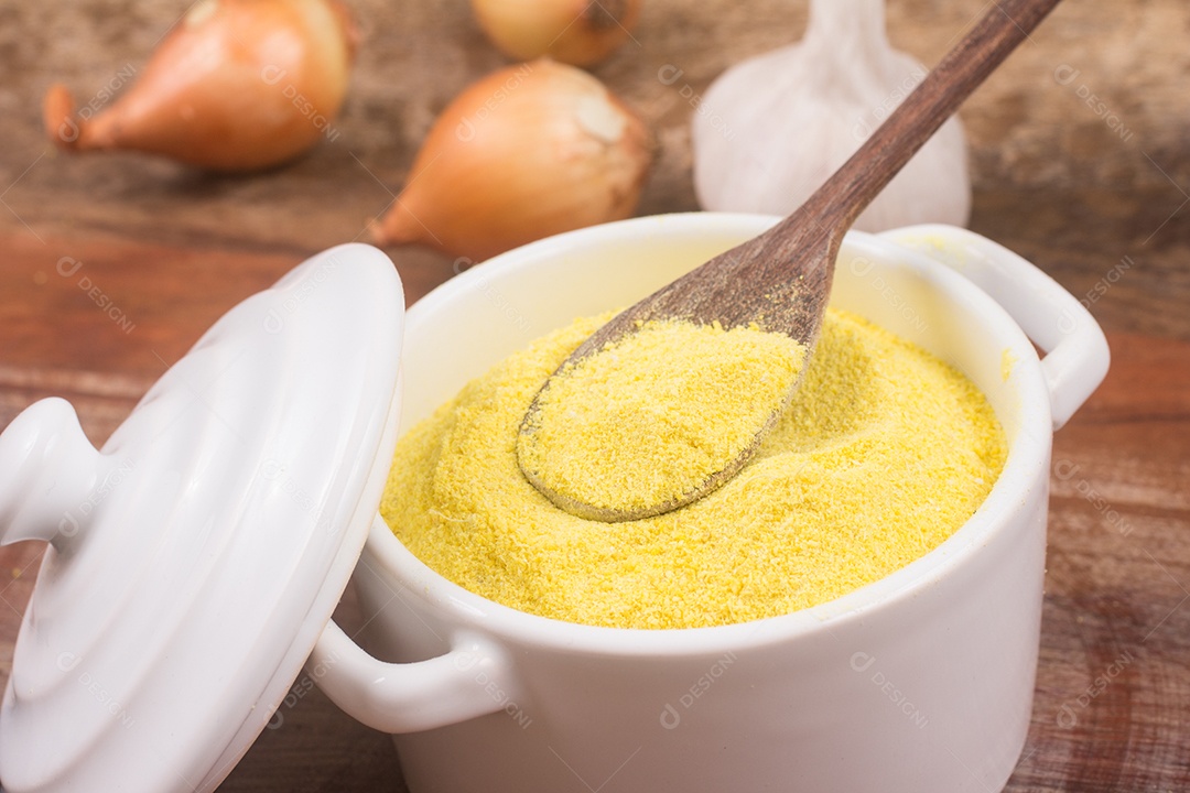Farinha de mandioca amarela em uma tigela sobre uma mesa de madeira