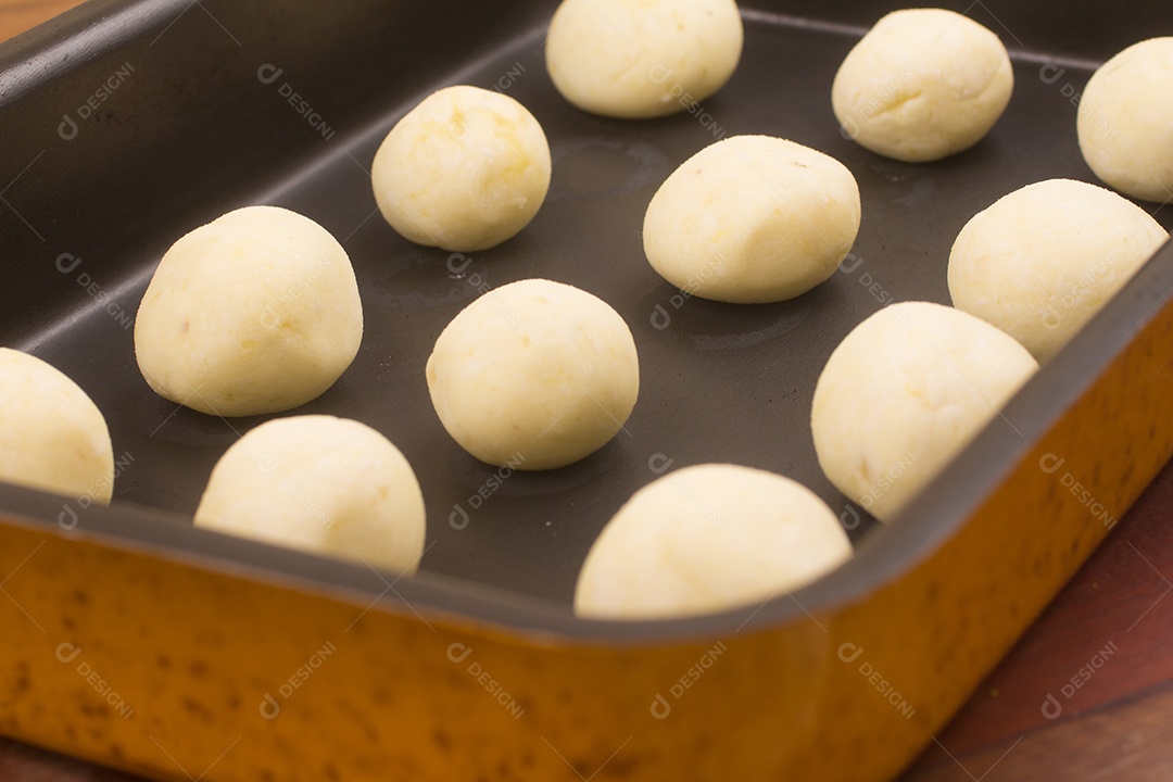 Pão de queijo cru brasileiro sobre uma mesa de madeira