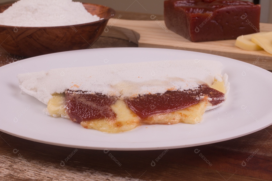 Tapioca recheada com goibada e queijo sobre mesa de madeira