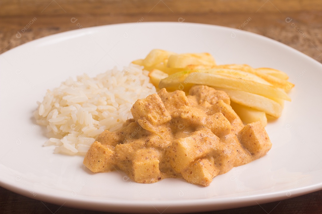 Strogonoff vegano com palmito, arroz e batata frita sobre mesa de madeira