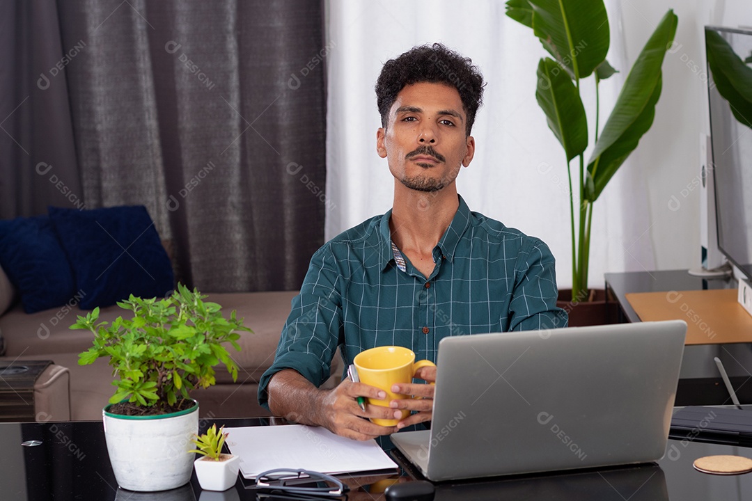 Jovem fazendo home office durante o dia na mesa com laptop