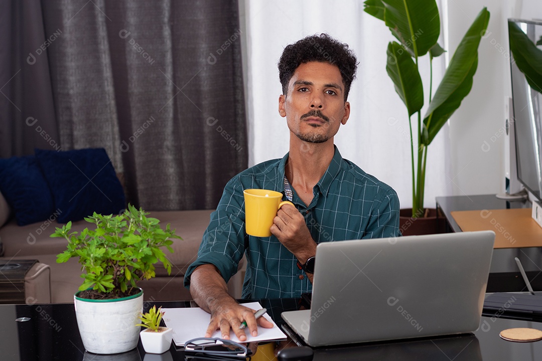 Jovem fazendo home office durante o dia na mesa com laptop