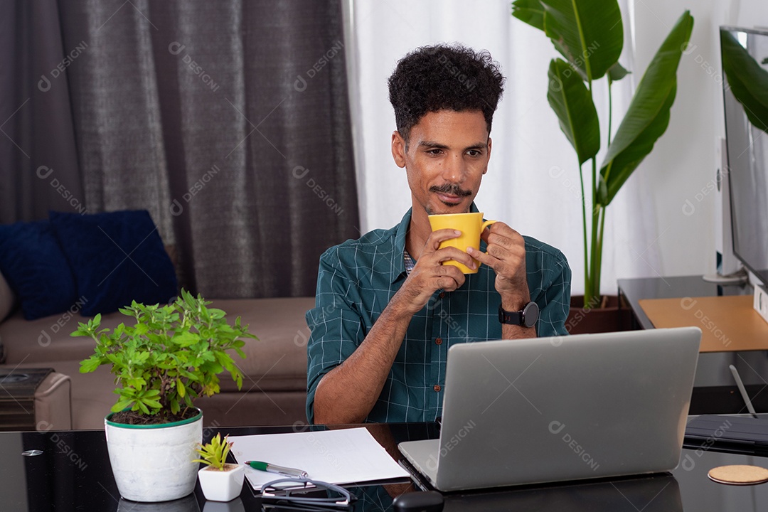 Jovem fazendo home office durante o dia na mesa com laptop