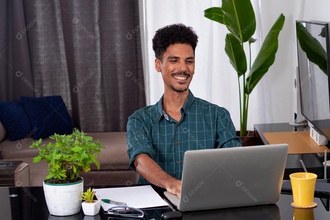 Jovem fazendo home office durante o dia na mesa com laptop